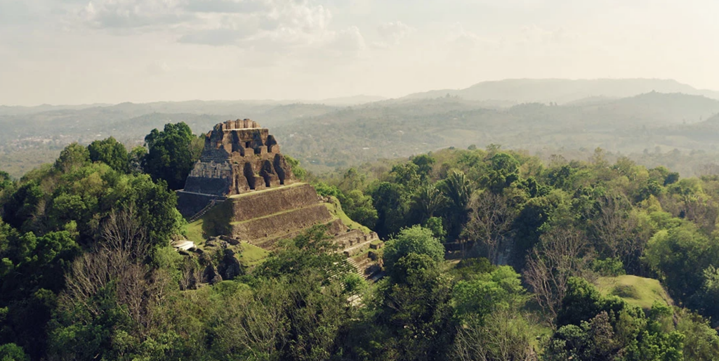 Aerial view of Xunantunich rising through the forest canopy. Create the best Belize Itinerary.
